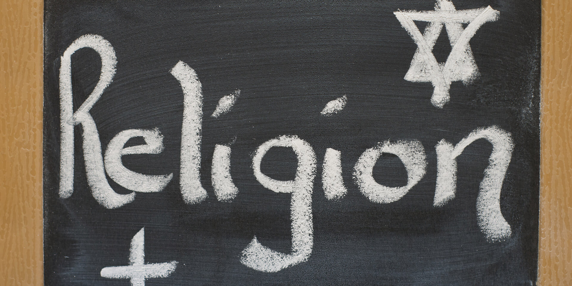Das Bild zeigt eine Tafel, auf der das Wort Religionsunterricht mit Kreide geschrieben ist Tafel mit dem Wort Religionsunterricht